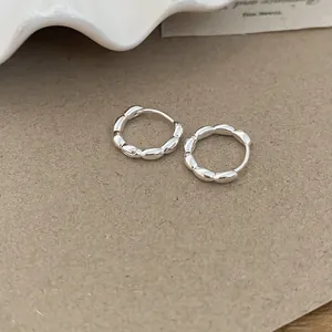 Detailed view of elegant silver scalloped hoop earrings on textured paper background