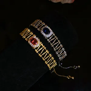 Detail view of gold and silver vintage hollowed bracelets with red and blue zircon stones