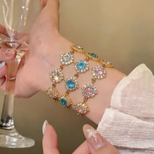 Eleganti bracciali placcati oro 18K con cerchi di zirconi colorati sul polso di una donna