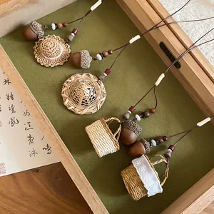 Handmade detail of New Chinese style acorn and straw hat necklaces in a wooden tray