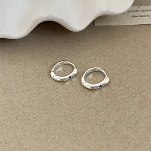 Close-up macro view of minimalist silver hoop earrings featuring blue zircon accents
