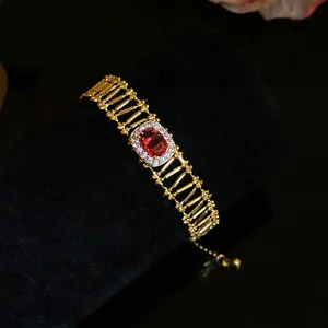 Close-up of luxury vintage hollow bracelet featuring an oval red zircon center stone