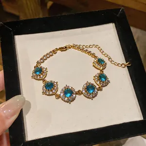 Dettaglio del bracciale placcato oro 18K con zirconi blu in una scatola regalo