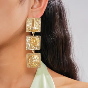 Close-up of unique gold square earrings featuring 3D nose and ear reliefs