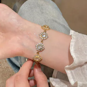 Primo piano di un bracciale in zircone placcato oro 18K con ciondoli floreali.