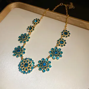 Detailed close-up of vintage gold necklace featuring intricate blue rhinestone flower pendants