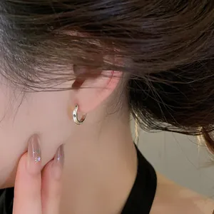 Close-up of a stylish silver zircon hoop earring on ear, showcasing minimalist design.