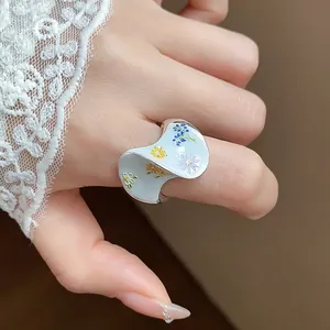 Vue rapprochée d'une bague argentée ondulée unique avec des motifs floraux en émail
