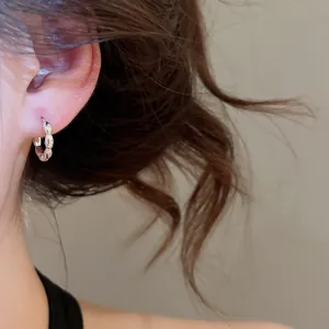 Close-up of minimalist sterling silver hoop earring with beaded scalloped edge design