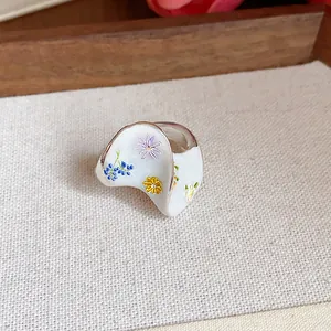 Vue détaillée d'une bague en émail blanc ornée de motifs floraux colorés peints à la main