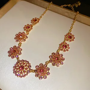 Detail view of a vintage palace style gold necklace with pink floral rhinestone pendants