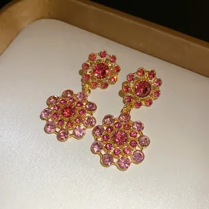 Macro detail of retro palace style floral earrings featuring pink and red rhinestones