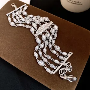 Vista dettagliata di un bracciale multistrato argento con strass e ciondolo a labbra.