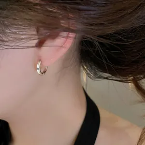 Detailed view of a small silver hoop earring with zircon star engraving on ear