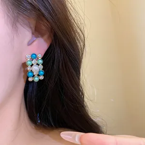 Gros plan de boucles d'oreilles de style royal avec perles et perles colorées sur modèle.