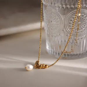 Dettaglio ravvicinato di una collana placcata oro con perla bianca e piccoli anelli