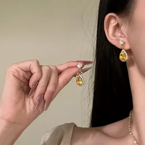 Detail of elegant teardrop yellow zircon earrings and necklace jewelry set on an Asian model