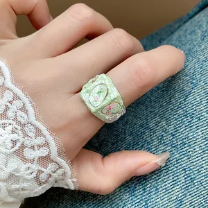Gros plan d'une bague fleur en émail vert frais avec de délicats accents de perles
