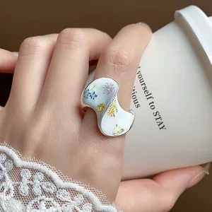 Gros plan d'une bague à fleurs en émail doux avec un design ondulé irrégulier au doigt.
