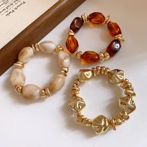Vista detallada de tres pulseras elásticas vintage de acrílico con cuentas doradas.