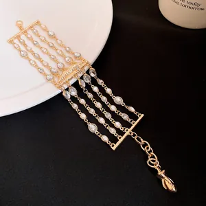 Vista dettagliata del lussuoso bracciale d'oro multistrato con strass e ciondolo a labbra