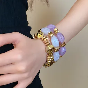 Detalle de pulseras elásticas de acrílico vintage con cuentas doradas en la muñeca.