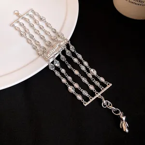 Vista dettagliata del bracciale multistrato in argento con strass e ciondolo a forma di labbra.