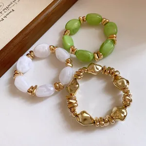 Primer plano de cuentas de acrílico y doradas en pulseras elásticas estilo retro