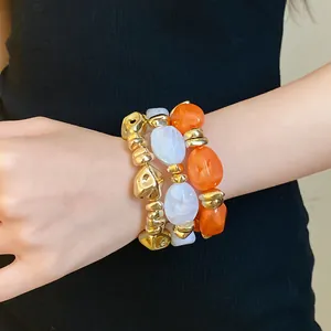 Primer plano de pulseras elásticas de acrílico de colores y cuentas doradas mate.