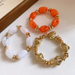 Pulseras elásticas de acrílico geométricas vintage en oro, naranja y blanco mármol.