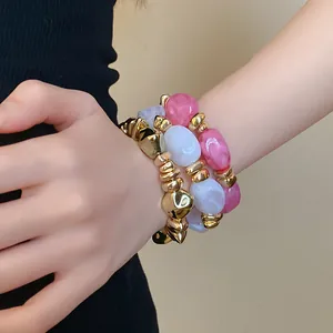 Primer plano de pulseras elásticas de acrílico geométricas retro en una muñeca.