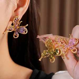 Exquisite gold plated butterfly earrings with colorful zircon stones shown on ear and hand