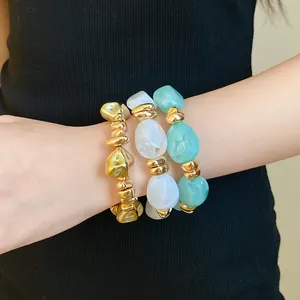 Primer plano de pulseras elásticas de acrílico irregular y oro en la muñeca