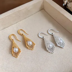 Close-up detail of French luxury hollow lace pendant earrings in gold and silver finishes.