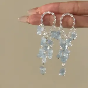 Detailed macro view showing the light blue stone tassels on silver rhinestone hoop earrings
