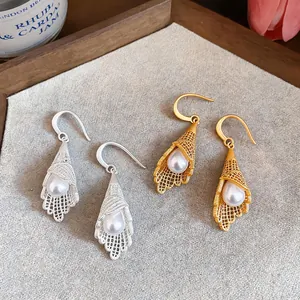 Detailed view of gold and silver hollow lace petal earrings with white pearls