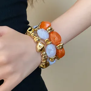 Primer plano de pulseras elásticas de acrílico geométrico con eslabones dorados