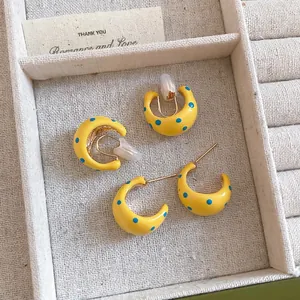 Yellow C-shaped enamel earrings with blue polka dots and clip-on option