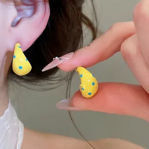 Fashionable cream yellow C-shaped hoop earrings featuring unique blue polka dot design