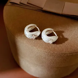 Elegant minimalist silver hoop earrings featuring a zircon star design on a brown box