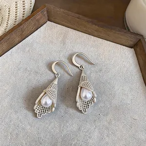 Close-up of French luxury silver hollow lace earrings with pearl detail