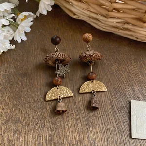 Close-up of handmade forest-style earrings featuring wooden beads and botanical seeds