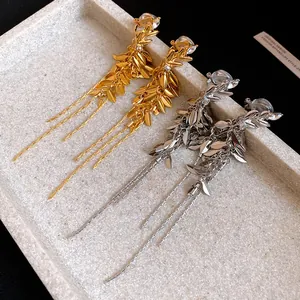 Detailed macro view of elegant gold and silver wheat spike tassel drop earrings.
