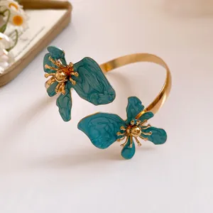 Detailansicht eines Vintage-Armreifs mit blaugrüner Emaille-Blume und Goldakzenten.