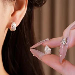 Close-up of silver star hoop earring with frosted texture and sparkling zircon inlay