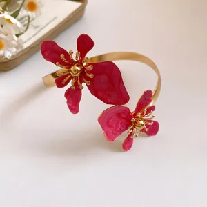 Detailaufnahme des goldenen Armreifs mit eleganten rosa Emaille-Blumen und Wirbelmuster-Dekor
