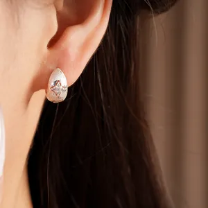 Close-up detail of a minimalist silver star hoop earring featuring sparkling zirconia stones