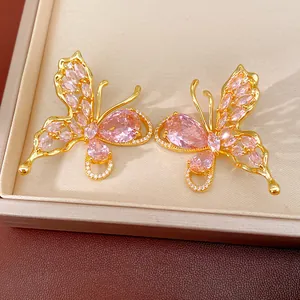 Detail view of gold plated butterfly stud earrings with sparkling pink cubic zirconia stones.