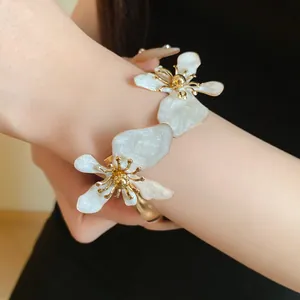 Detaillierte Ansicht eines eleganten goldenen Metall-Emaille-Blumen-Armreifs mit Blüten