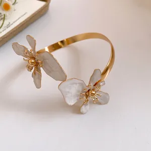 Nahaufnahme eines goldenen Armreifs mit eleganten weiß marmorierten Emaille-Blütenblättern